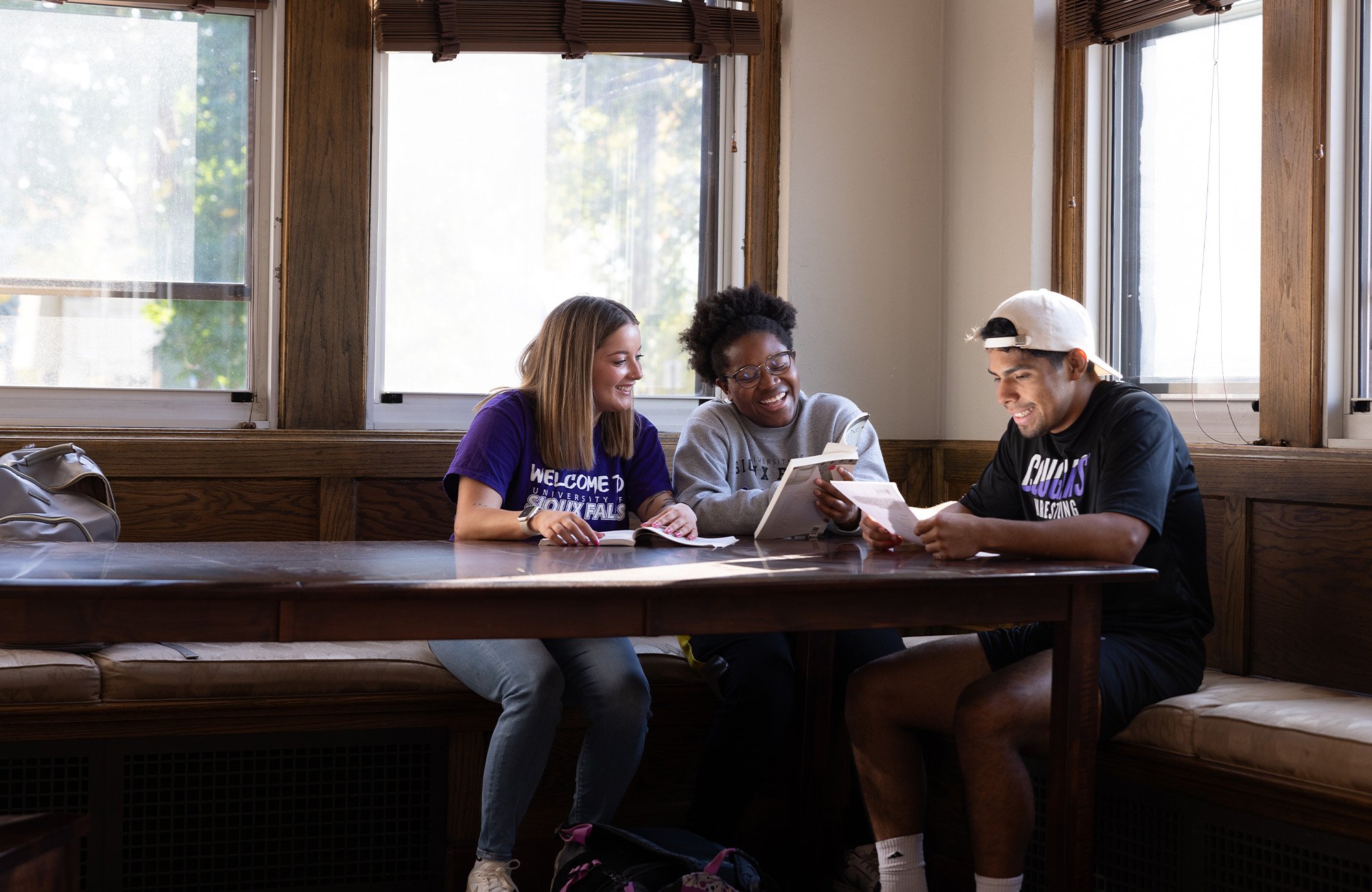 Three students gather to talk do their homework together